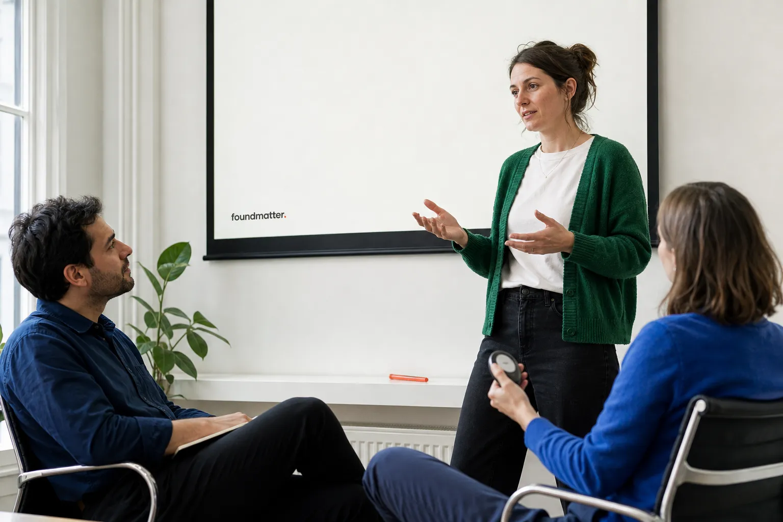 AI-generated scene: A founder rehearses her pitch with two listeners.